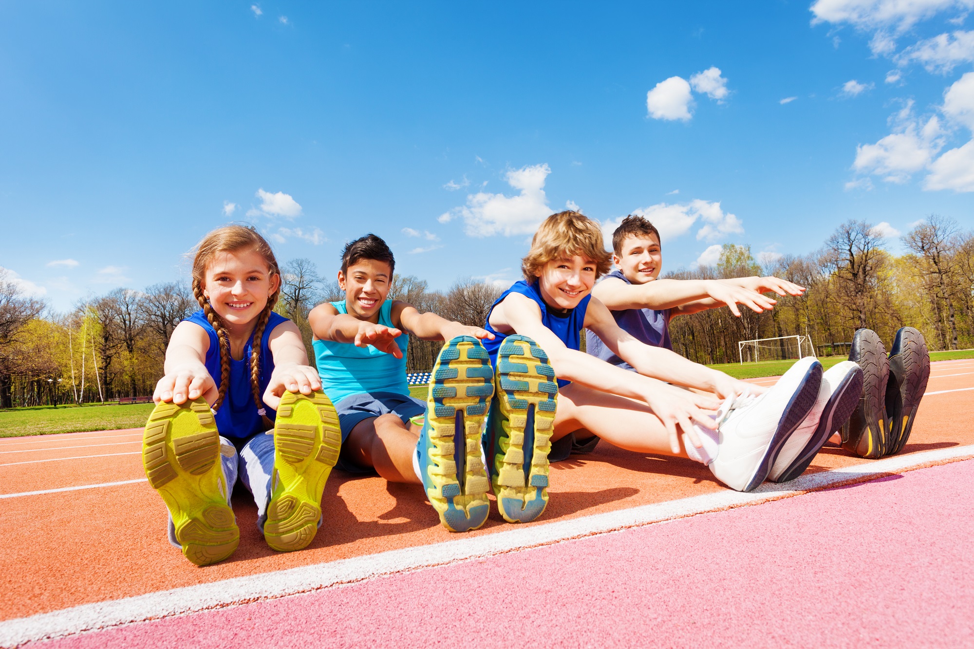 Gelukkige kinderen aan het rekken op een atletiekbaan